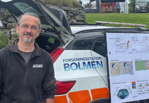 Forskningsstation BOlmens föreståndare Juha Rankinen framför en skylt som visar forskningsarbetet på stationen.