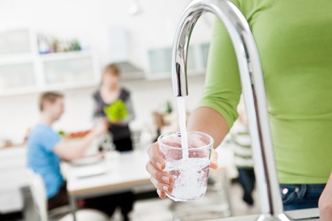 Vattenkran som fyller ett glas m vatten