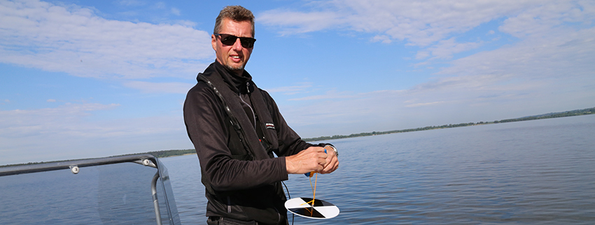 Mikael Henriksson tar prover på Vombsjöns vatten